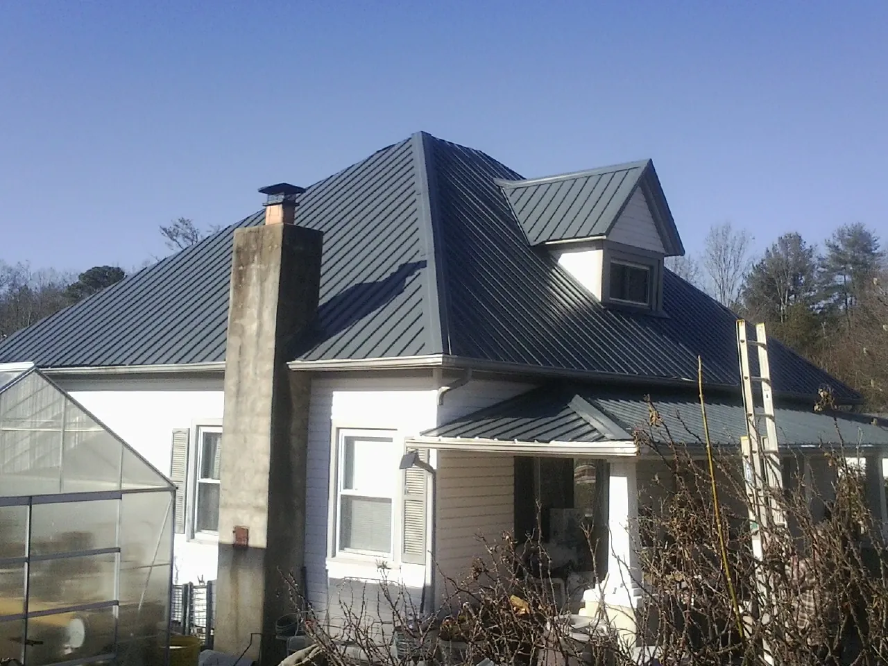 Dark blue standing seam metal roof on a white farmhouse with dormer — Slate & Tile Roof Repair by Roofing Brothers in Funston