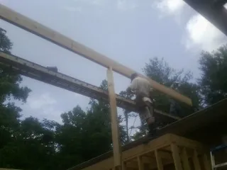 Carpenter setting a ridge beam over a new addition frame — Ice Dam Removal by Roofing Brothers in Funston