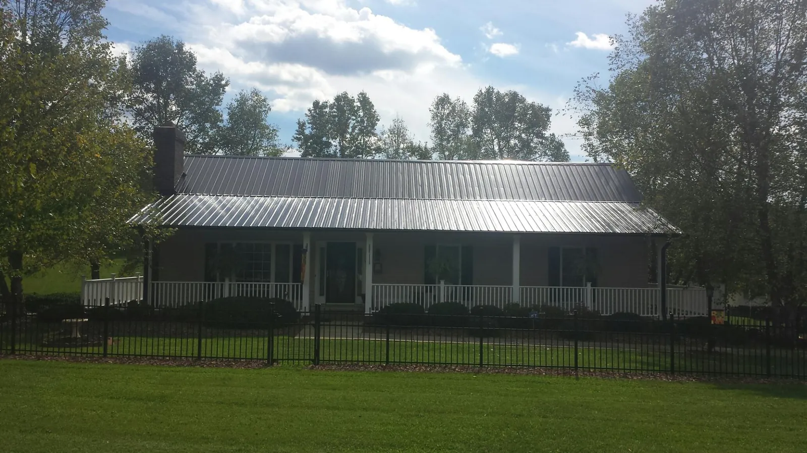 Gray metal roof on a brick ranch with a full width front porch — Gutter Guard Installation work by our crew in Funston