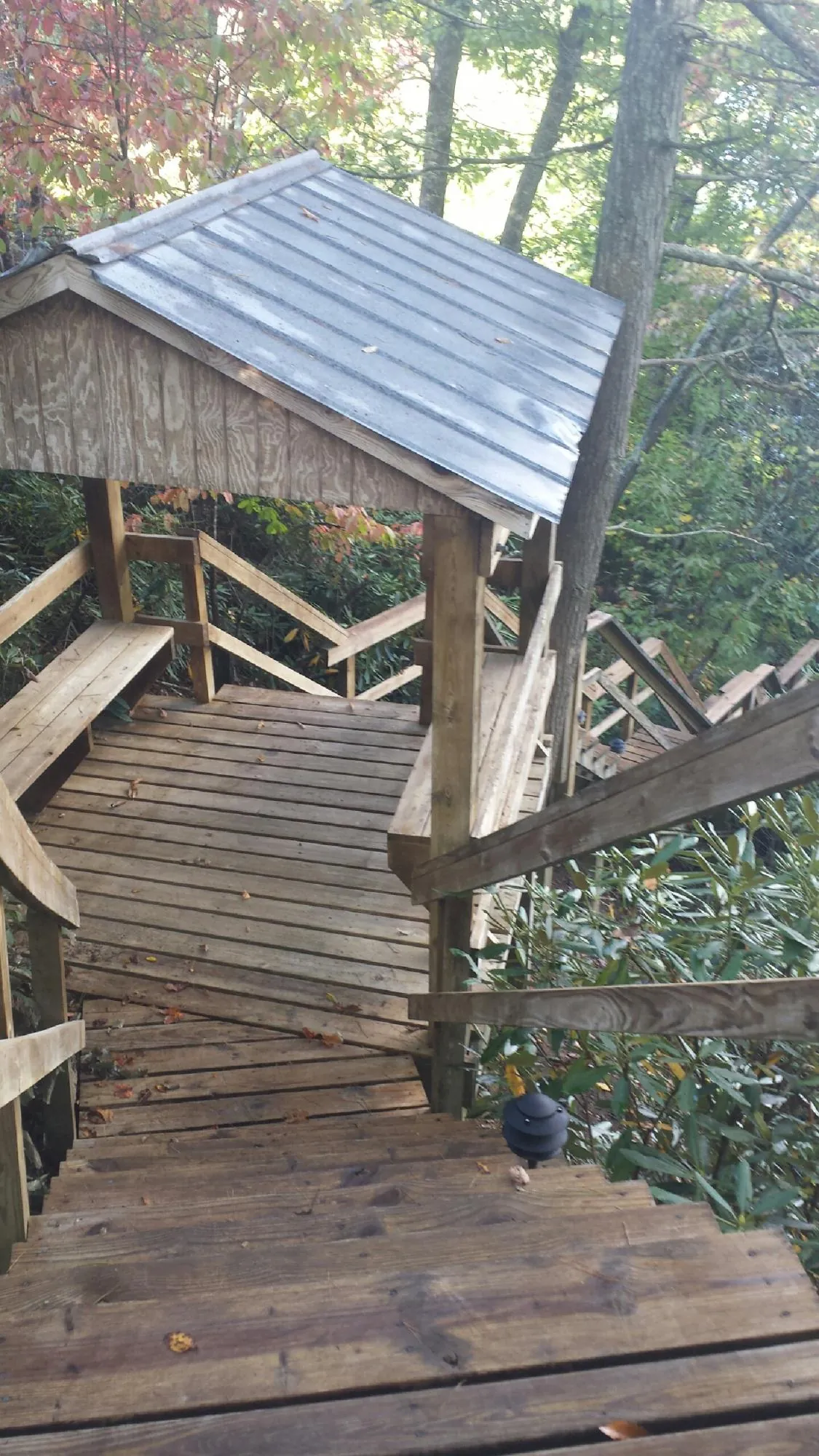 Metal roofed shelter over wooden steps on a wooded walkway — Skylight Repair & Installation work by our crew in Funston