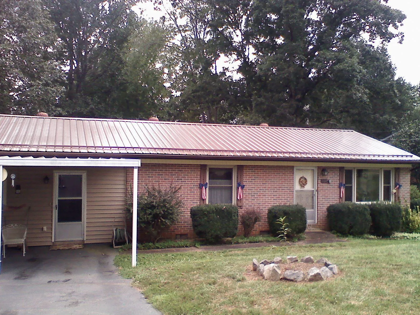 Bronze metal roof and carport on a brick ranch home — Roof Repair work by our crew in Funston