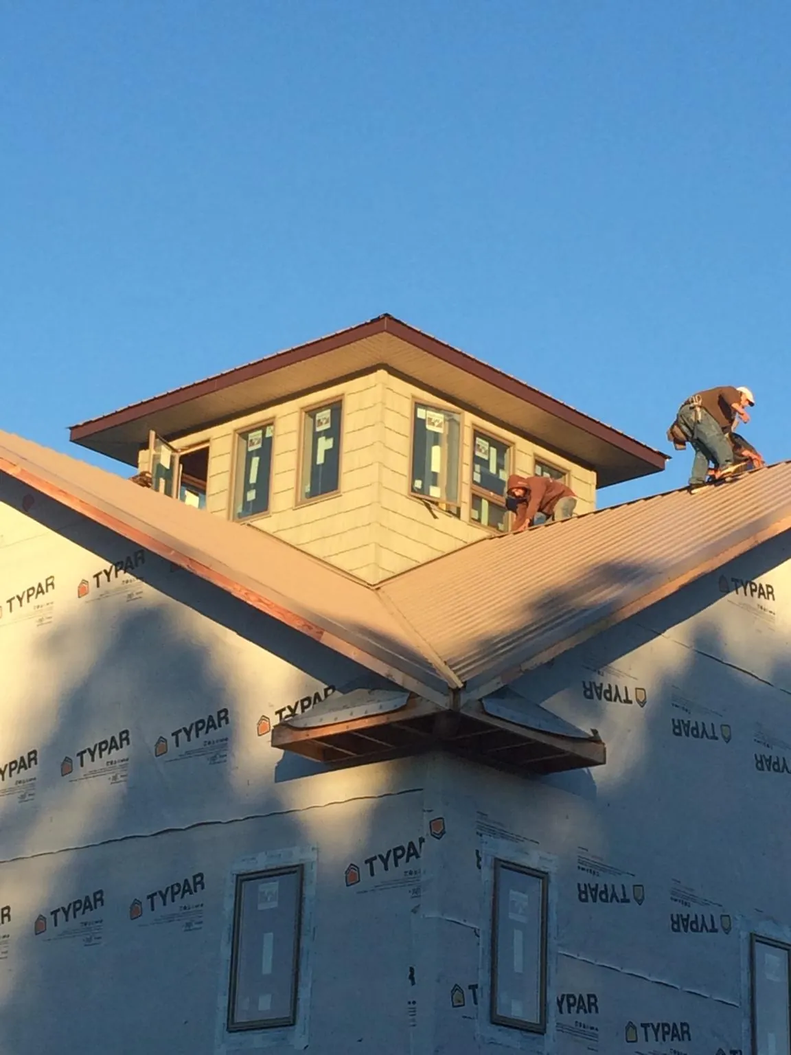 Roofers working around a rooftop cupola on a new metal roof at sunset — Roof Waterproofing in Funston by Roofing Brothers